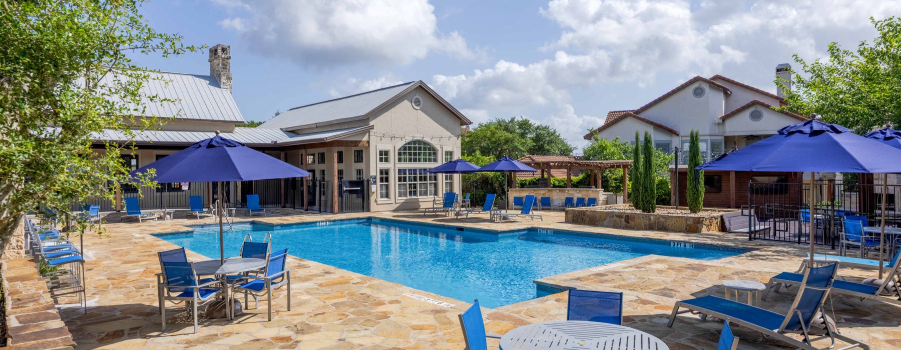 A pool with deck and blue umbrellas